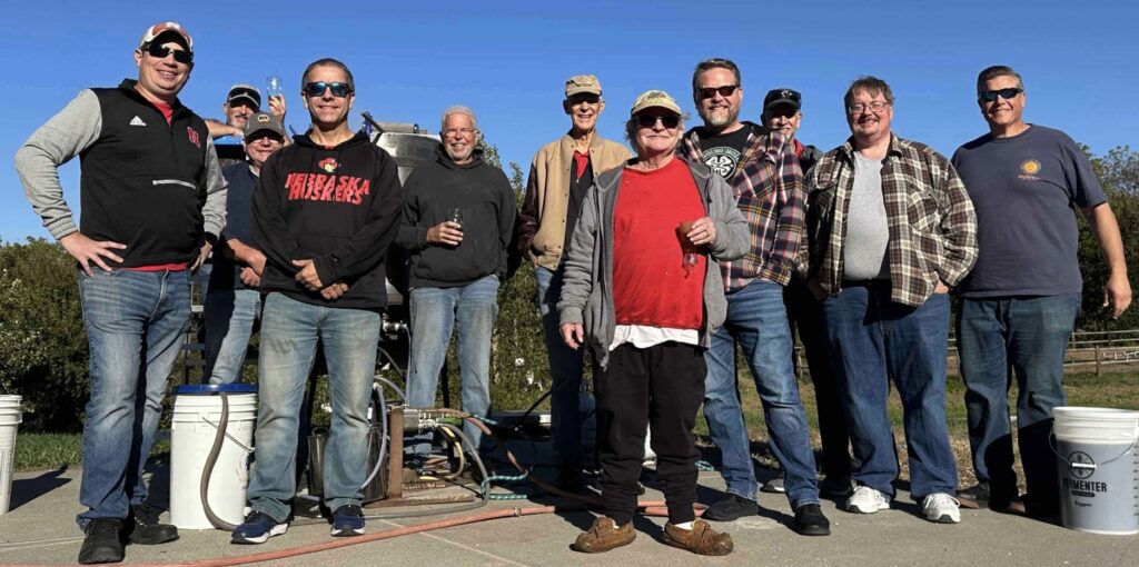 Omahops club members gathered outdoors around brewing equipment